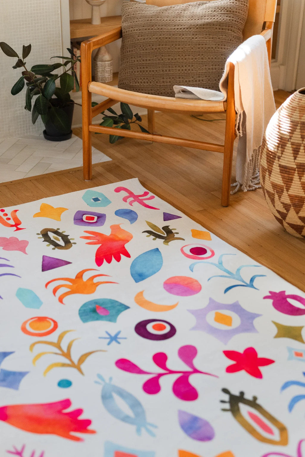 Colorful living room rug near a wood chair and woven basket, with a balanced repeat of graphic floral and celestial shapes