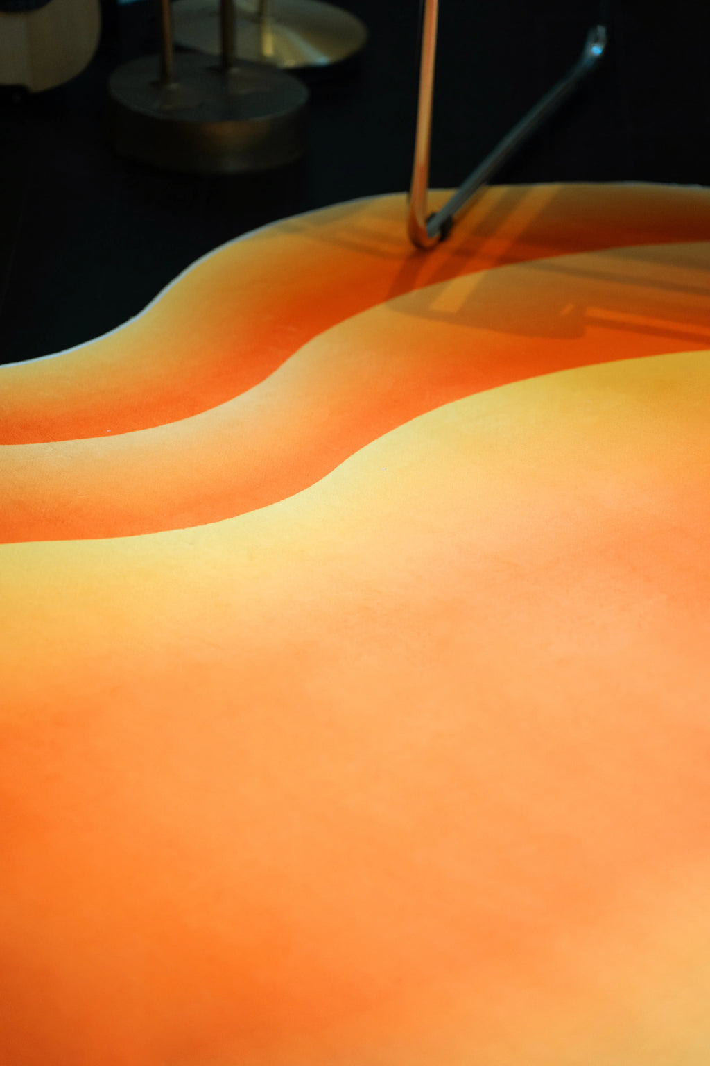 Orange Modern Abstract Wavy Rug under a chrome chair, highlighting the curved bands and soft tonal shading