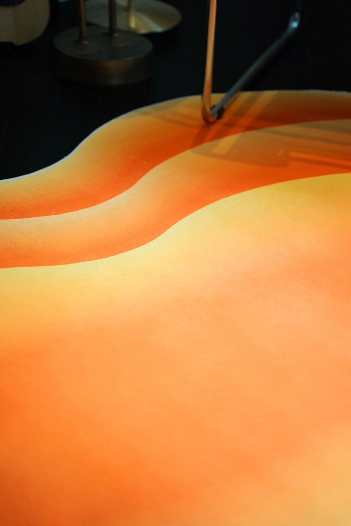 Orange Modern Abstract Wavy Rug under a chrome chair, highlighting the curved bands and soft tonal shading