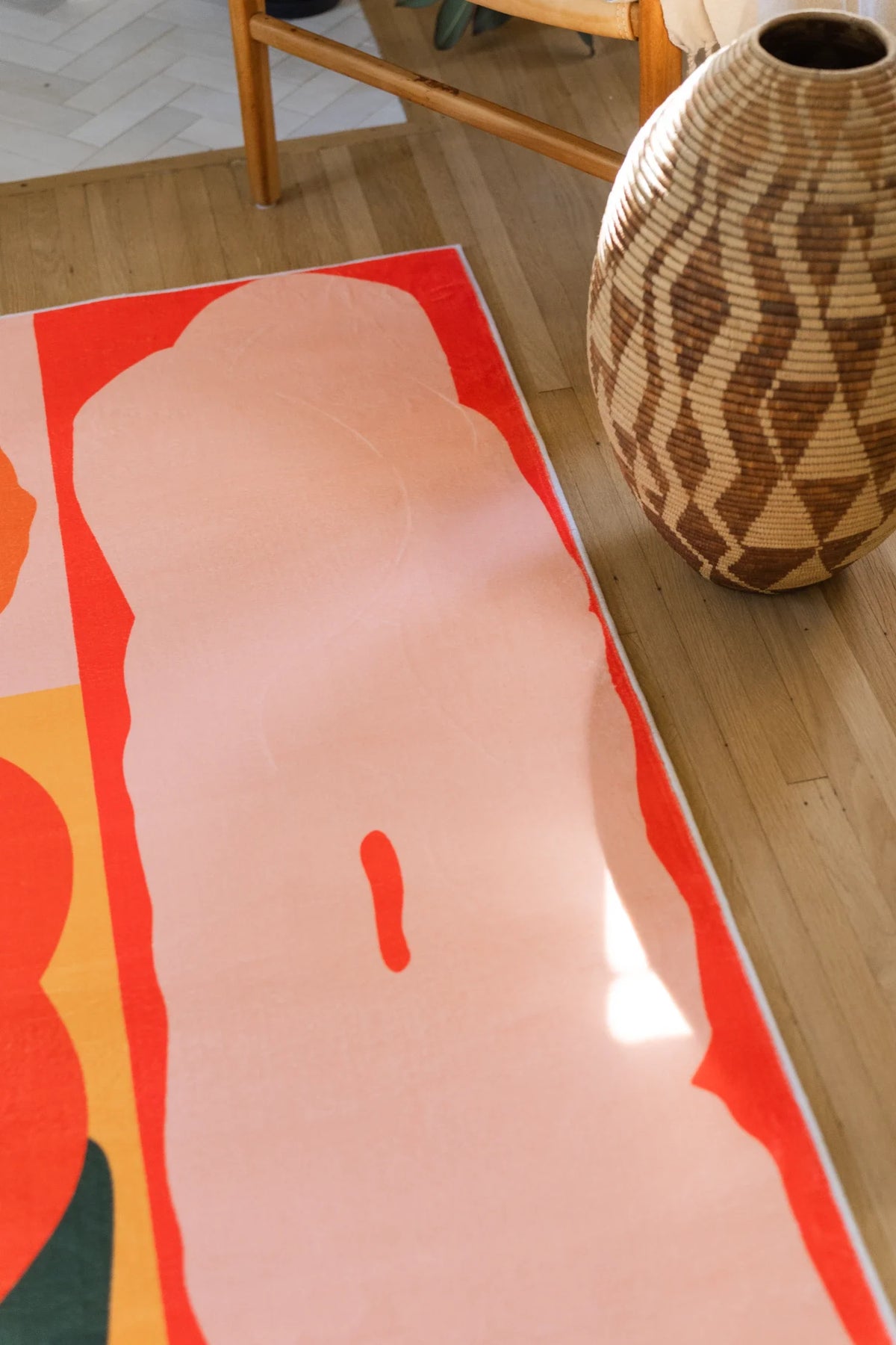 Vertical detail near a woven basket showing a long blush pink petal form bordered by orange and red bands