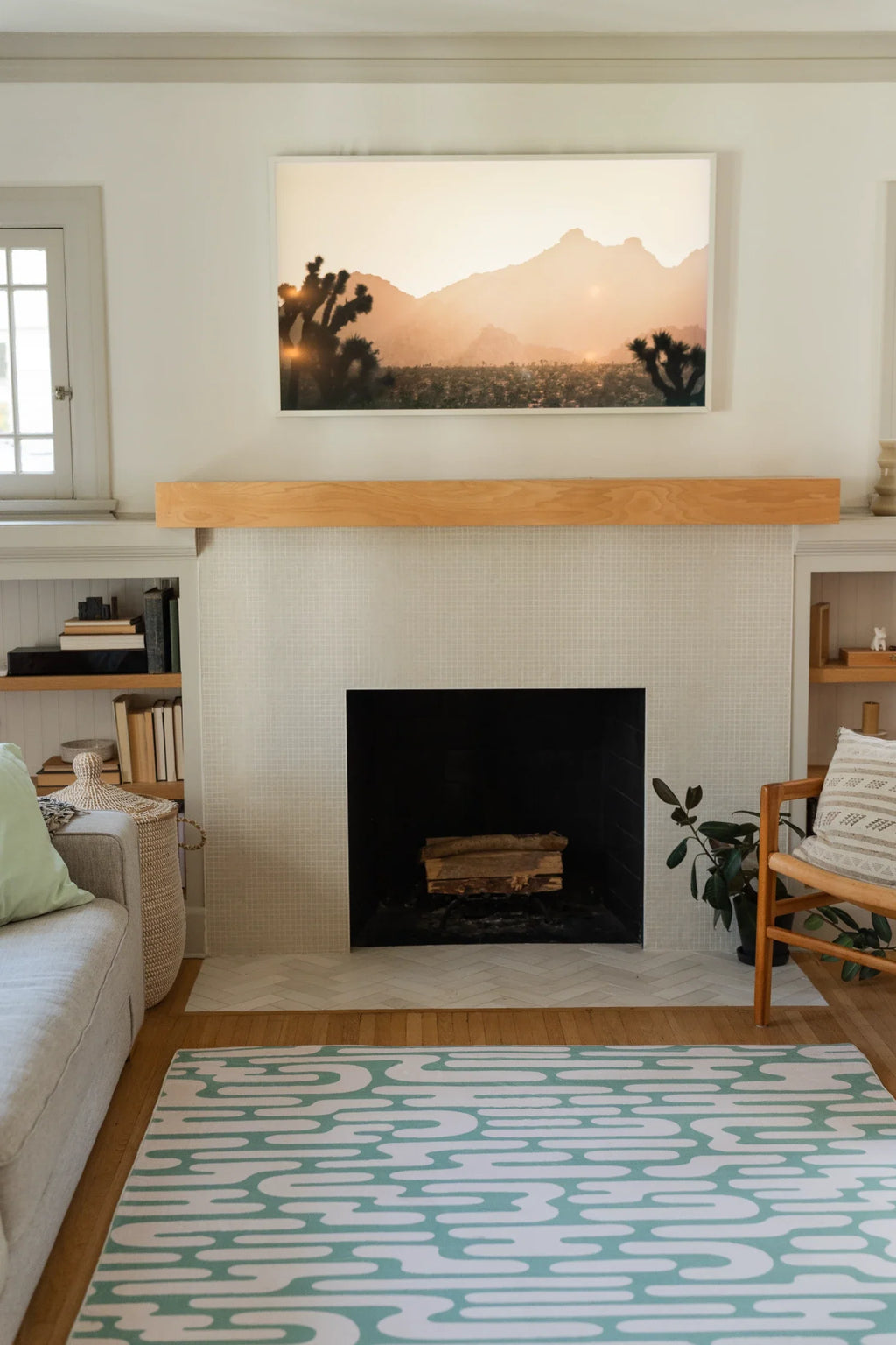 Green Abstract Wavy Area Rug stretching through an airy living room toward a fireplace and open shelving