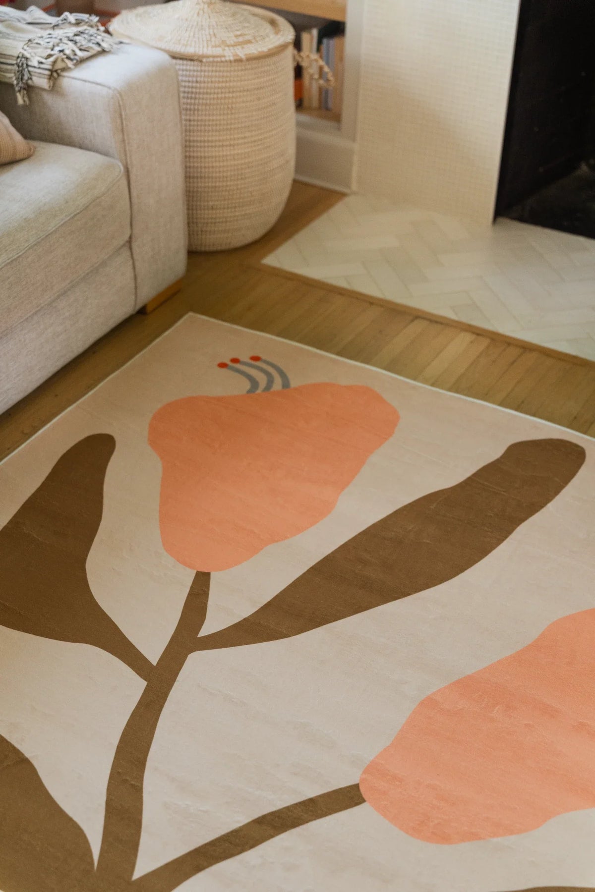 Floral rug detail near the fireplace, with a peach bud, brown stem, and rounded leaf forms on a beige field