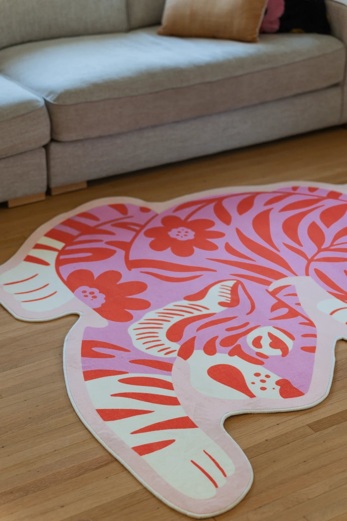 Close crop of the tiger shaped rug under the sofa edge, with a white paw outline and vintage striped pattern