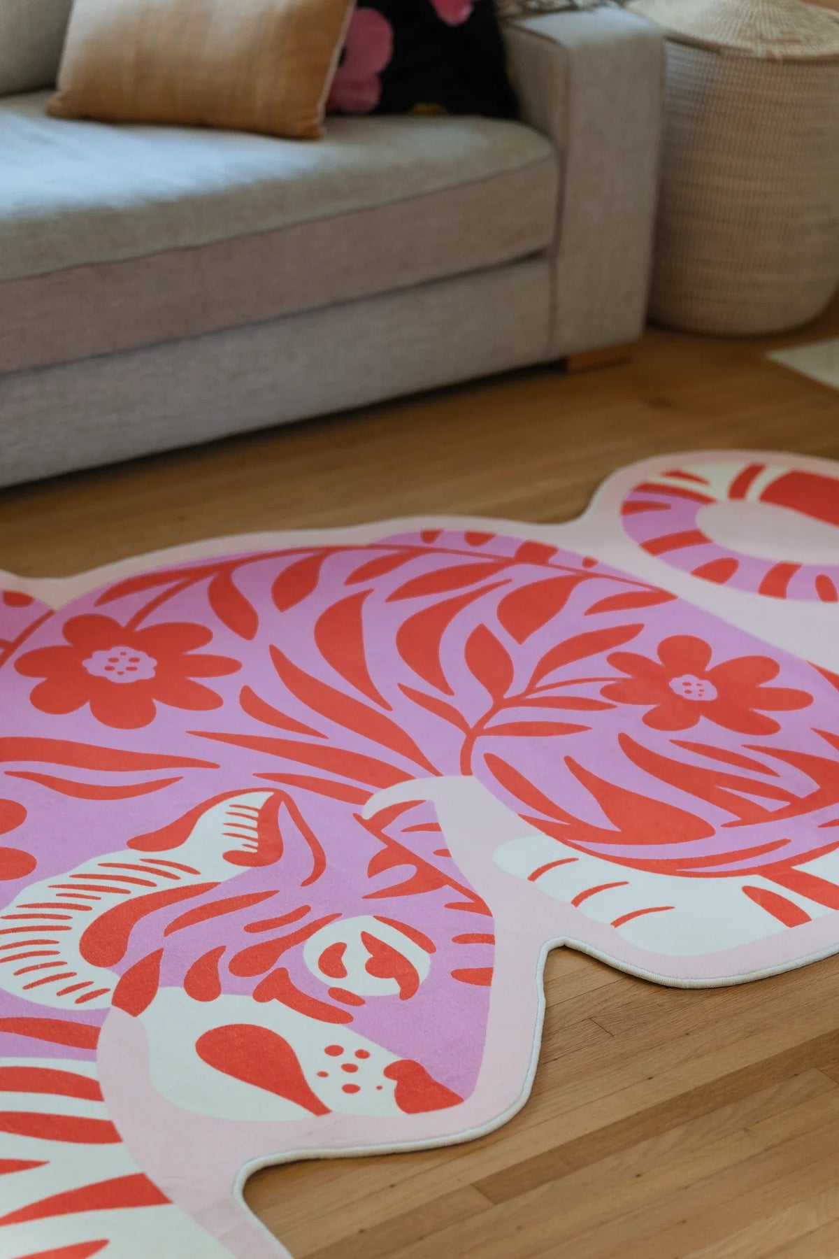 Partial view beside a beige sofa, highlighting the tiger rug's rounded back, coral stripes, and floral detailing