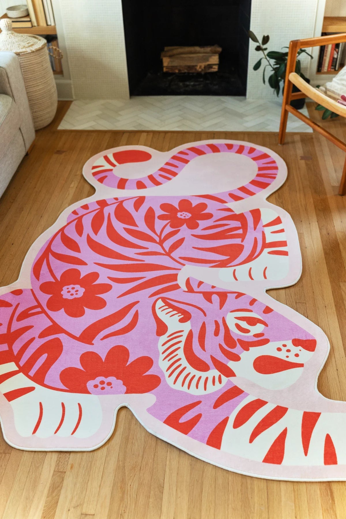 Tiger shaped area rug stretched toward the fireplace, showing the curled tail, white border, and pink graphic body