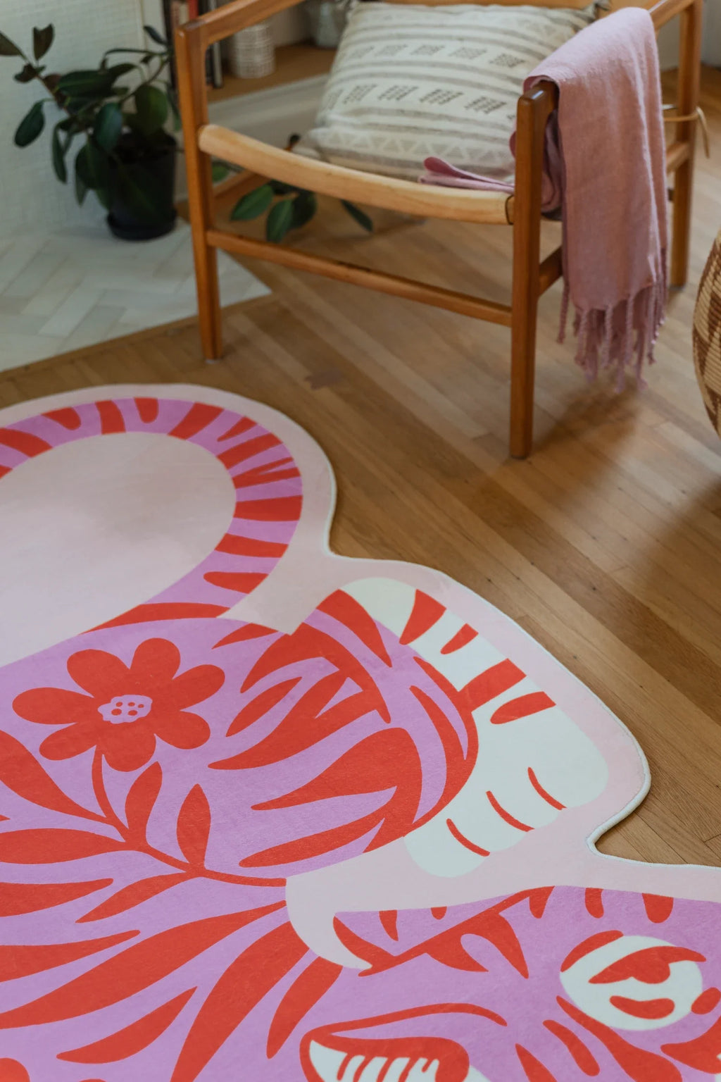 Close up of the tiger shaped rug near the chair leg, showing the curved white border and coral graphic stripes