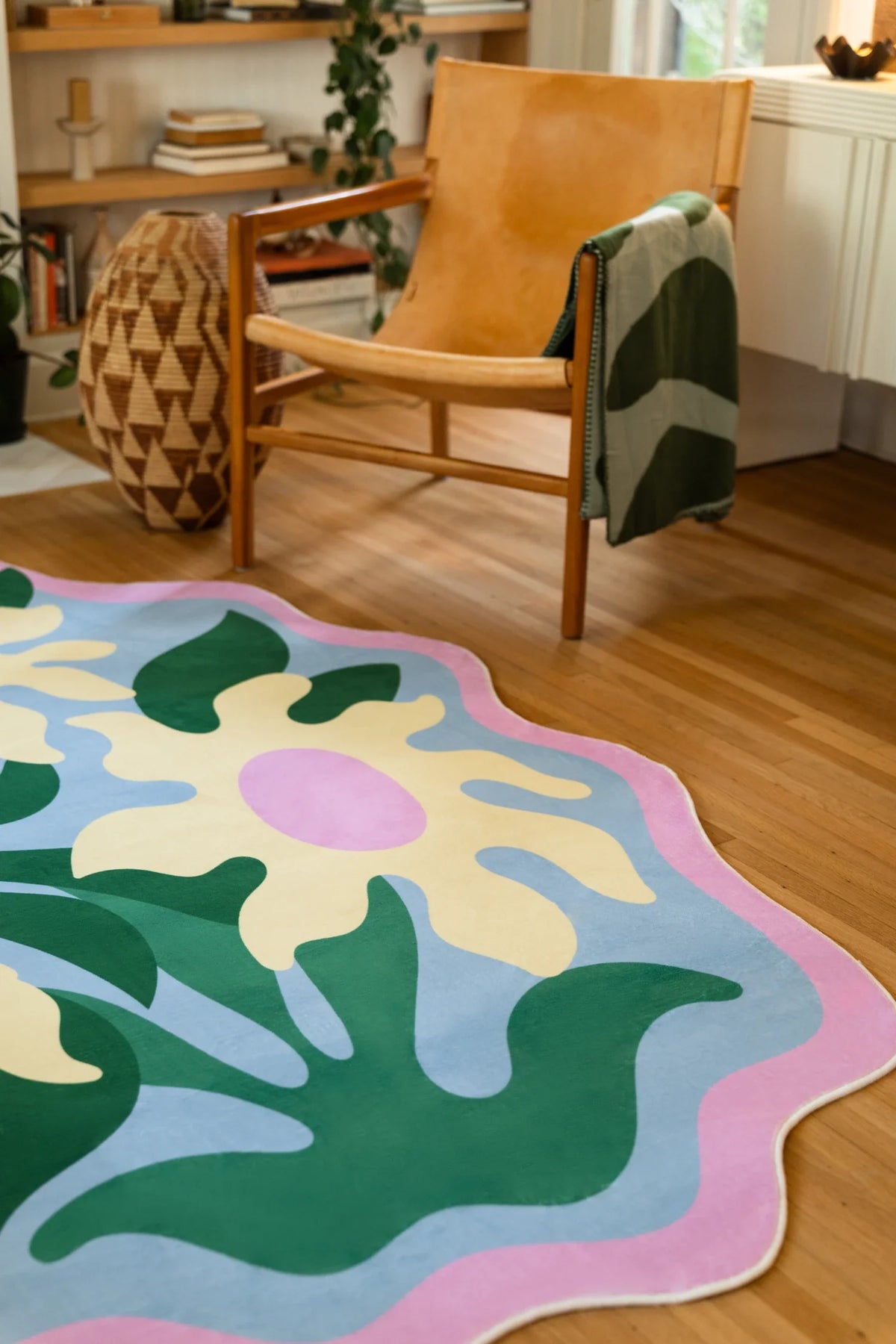 Wavy edge floral area rug in a bright sitting area, with pastel blossoms and deep green stems on a soft blue field
