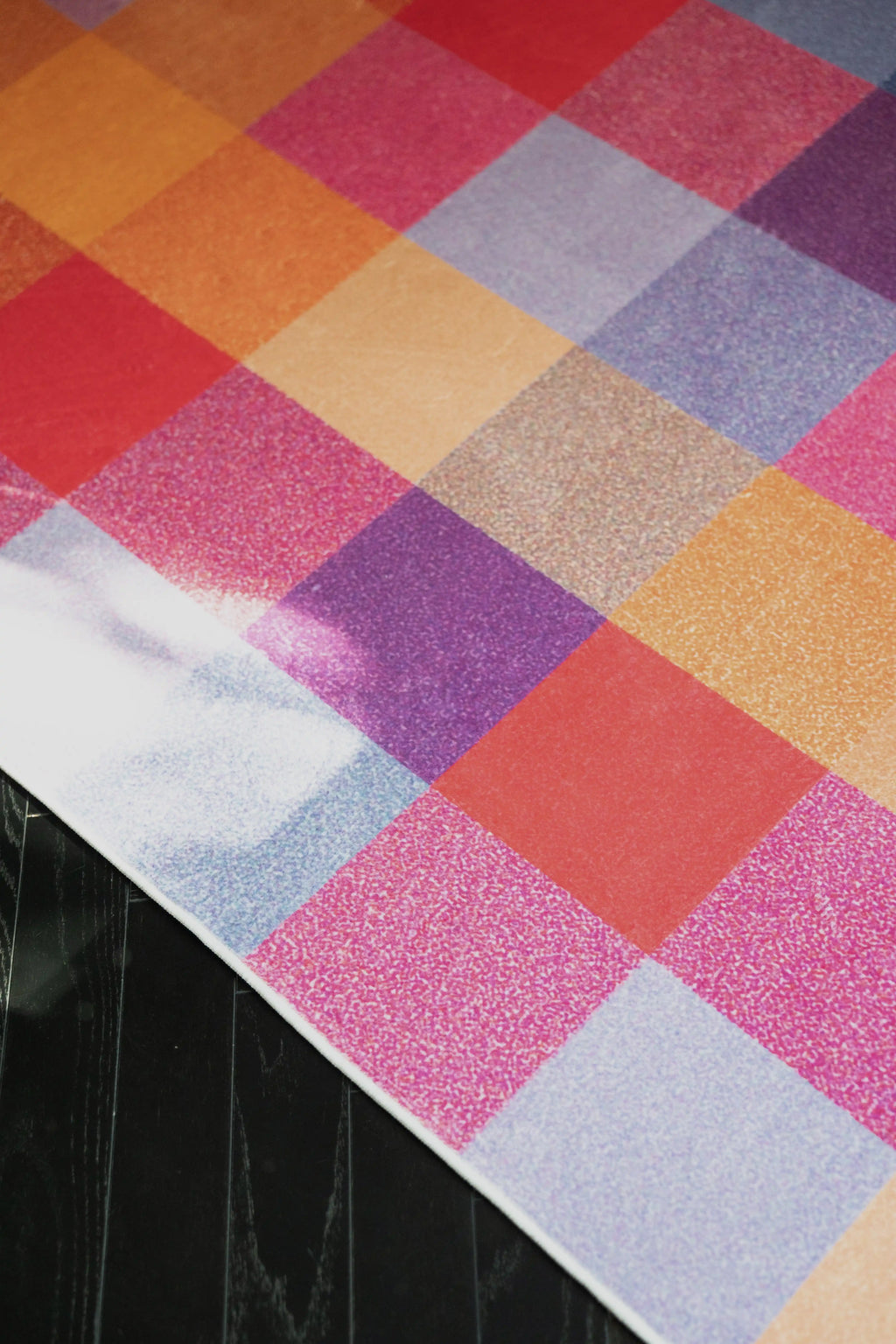 Corner close up of the rust red vintage rug with soft grid lines and layered color blocks