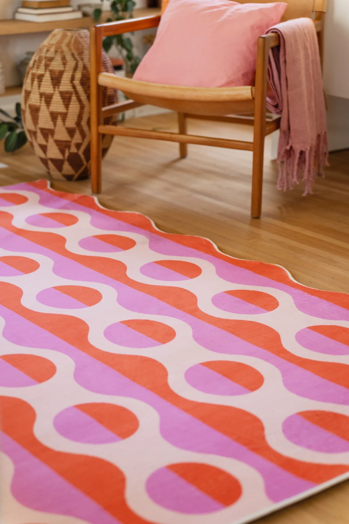 Pink and orange striped rug beneath a wood chair with a draped throw, showing repeating oval pattern blocks
