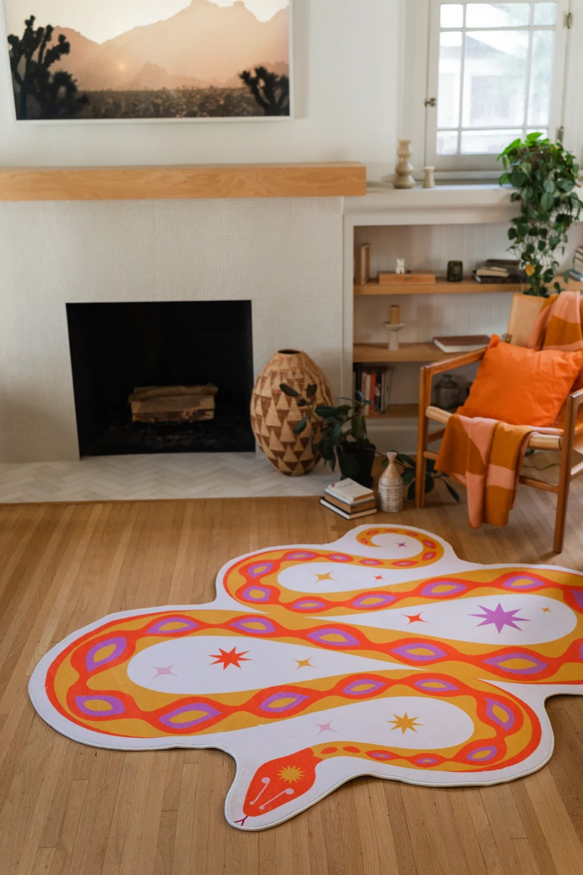 Orange snake rug in front of the fireplace and beside a wood chair, with layered curves on a light wood floor