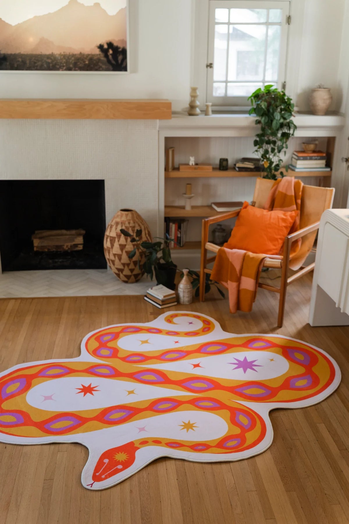 Playful orange irregular shaped rug near the fireplace, showing a winding snake form with pink and yellow spot details