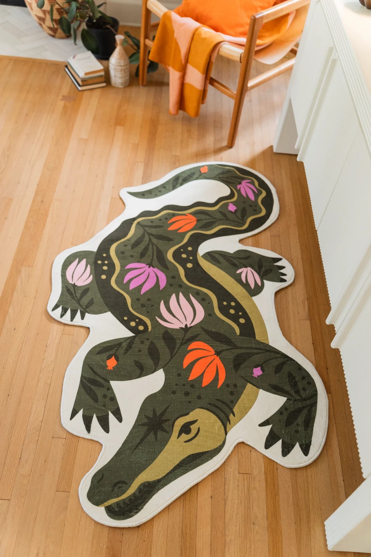Graphic crocodile shaped area rug near white cabinetry, with floral details across the dark green body