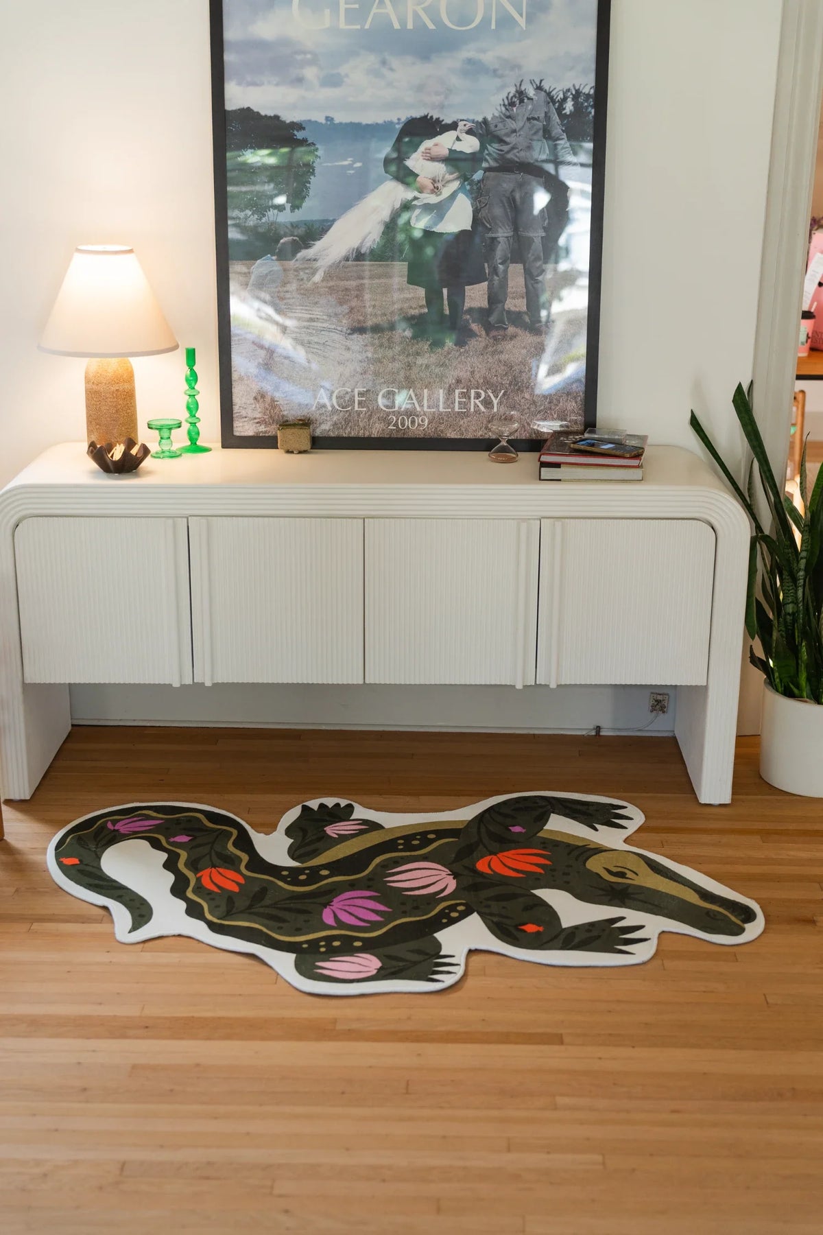 Animal shaped crocodile rug beneath framed art and beside a white cabinet in a creative living corner