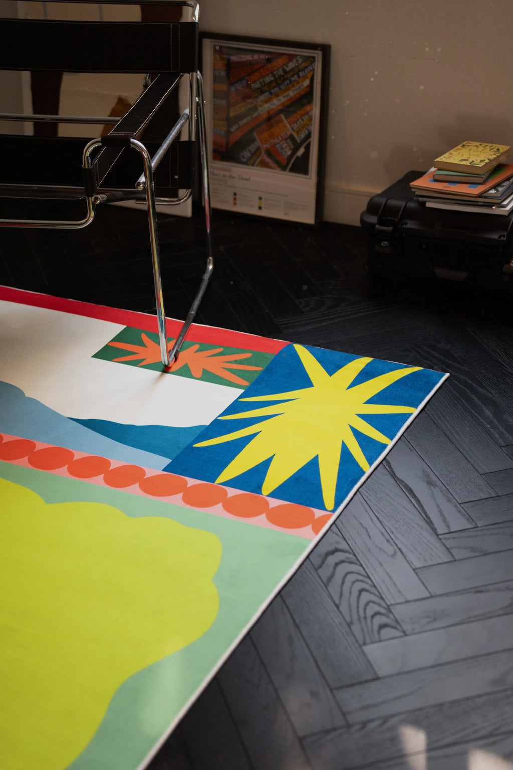 Mid century flower rug under a chrome chair, showing the blue corner panel and yellow starburst motif