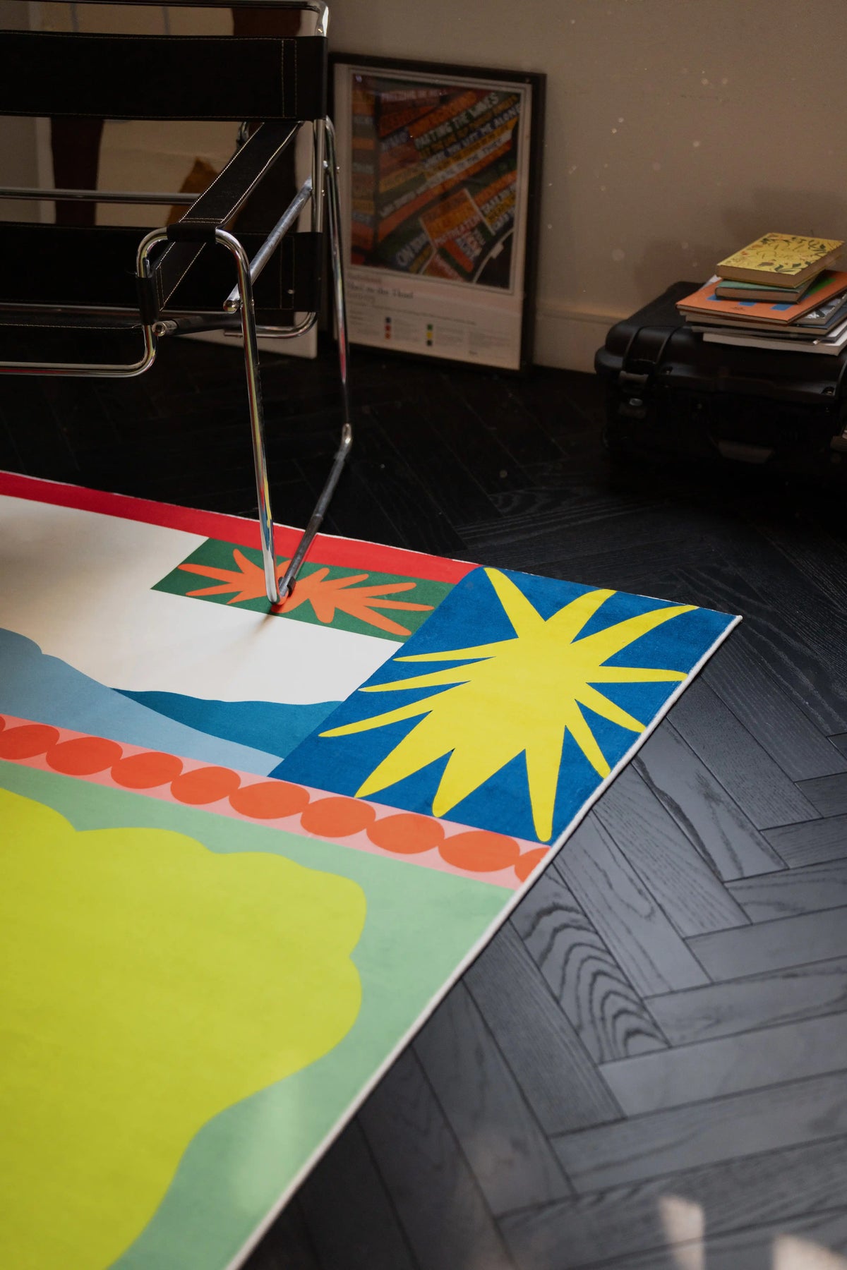 Mid century flower rug under a chrome chair, showing the blue corner panel and yellow starburst motif