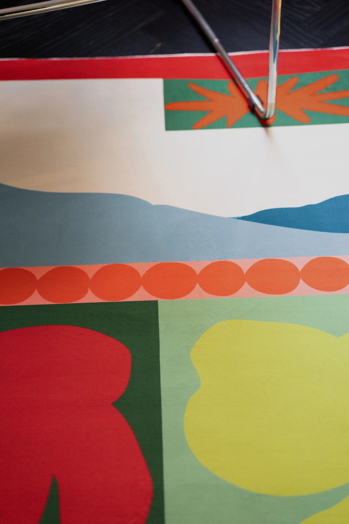 Rug corner close up with a yellow starburst, orange dot border, blue band, and lime green color block