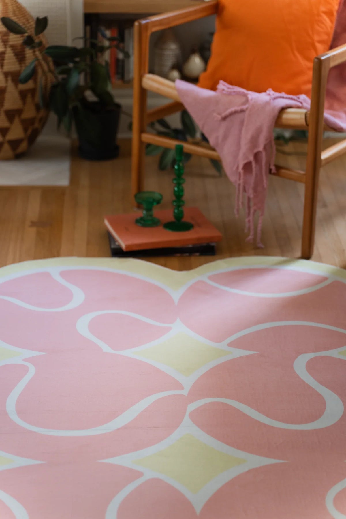 Close up of the pink rug beside a green lamp base, showing rounded forms and white tennis court lines