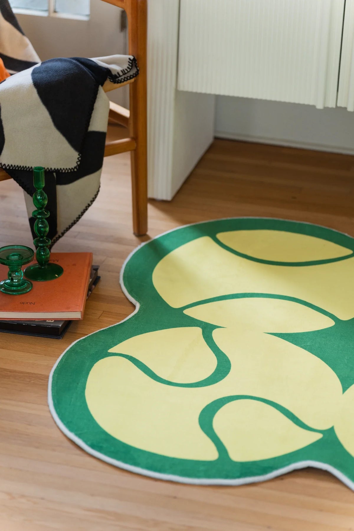 Partial yellow tennis rug beside a wood chair and white cabinet, showing curved green linework