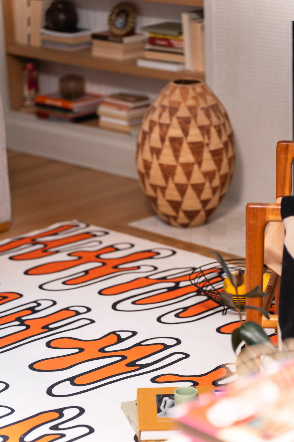 Beige abstract rug beside a geometric wooden vase and built-in living room shelves.