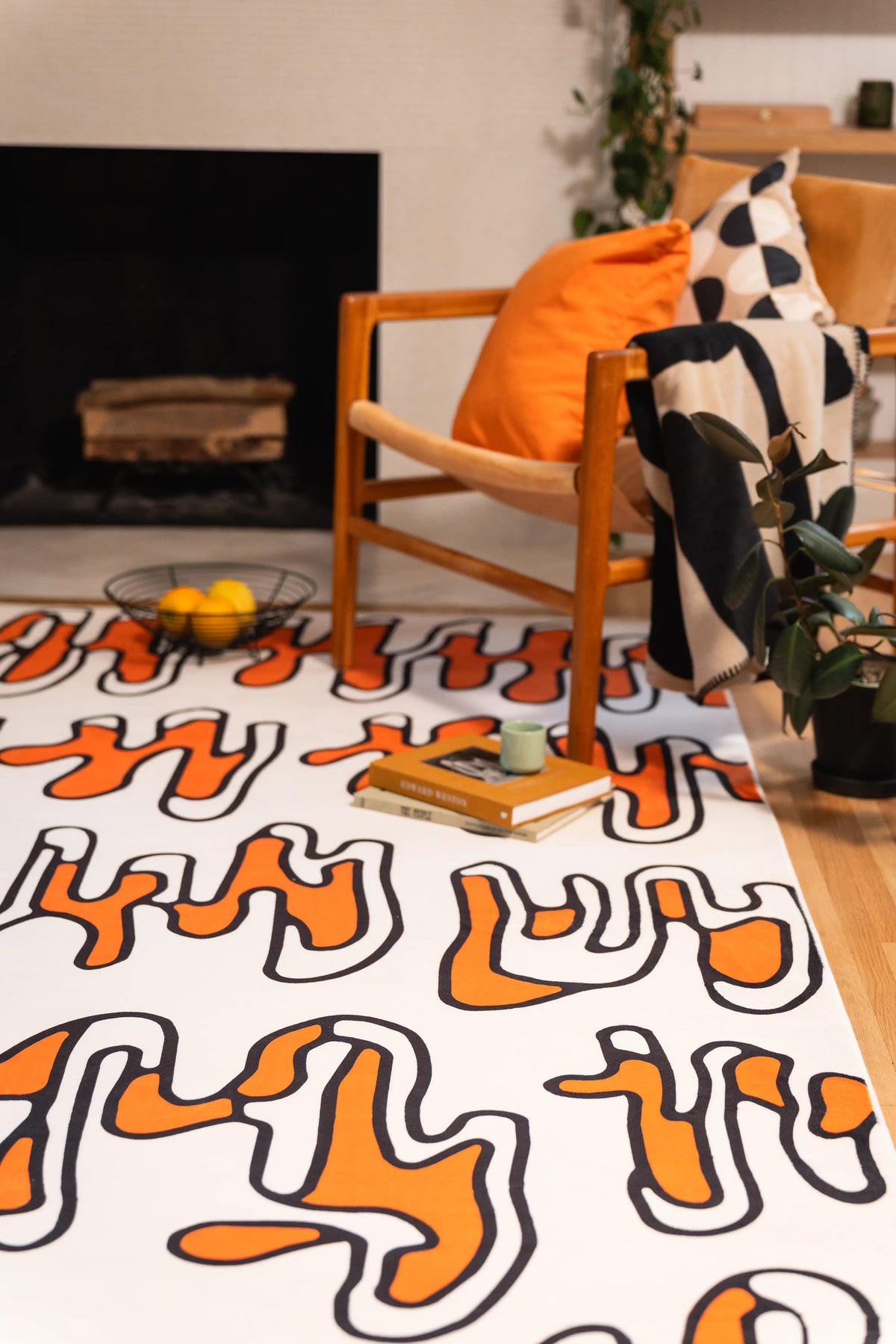 Beige squiggle rug beneath a wooden armchair in front of a black fireplace.
