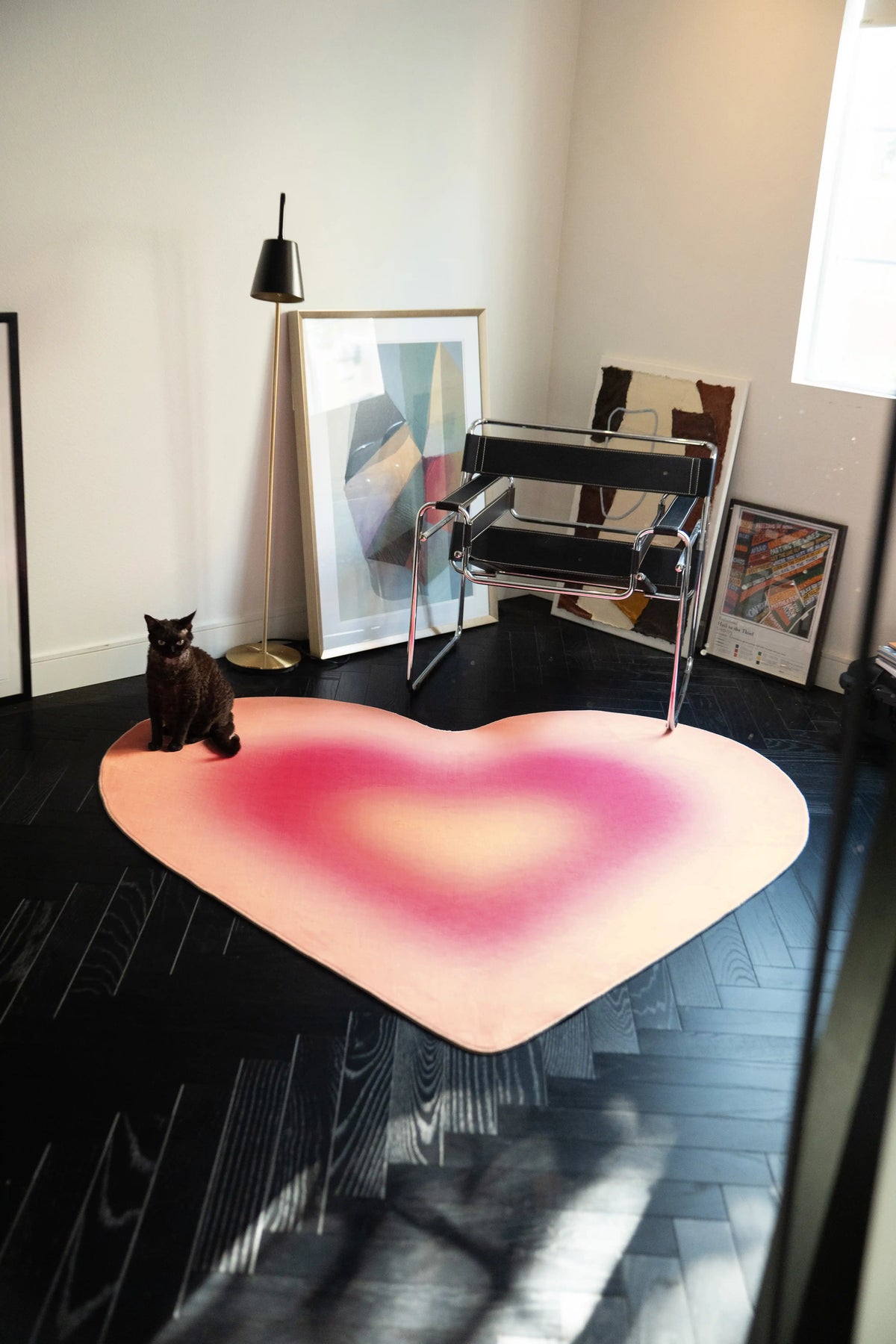 Heart shaped rug in a modern corner with a chrome chair, floor lamp, framed art, and dark wood floor