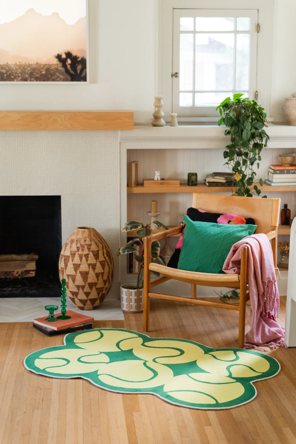 Wide room view of the yellow tennis rug near a fireplace, shelving, and a wood chair with bright pillows