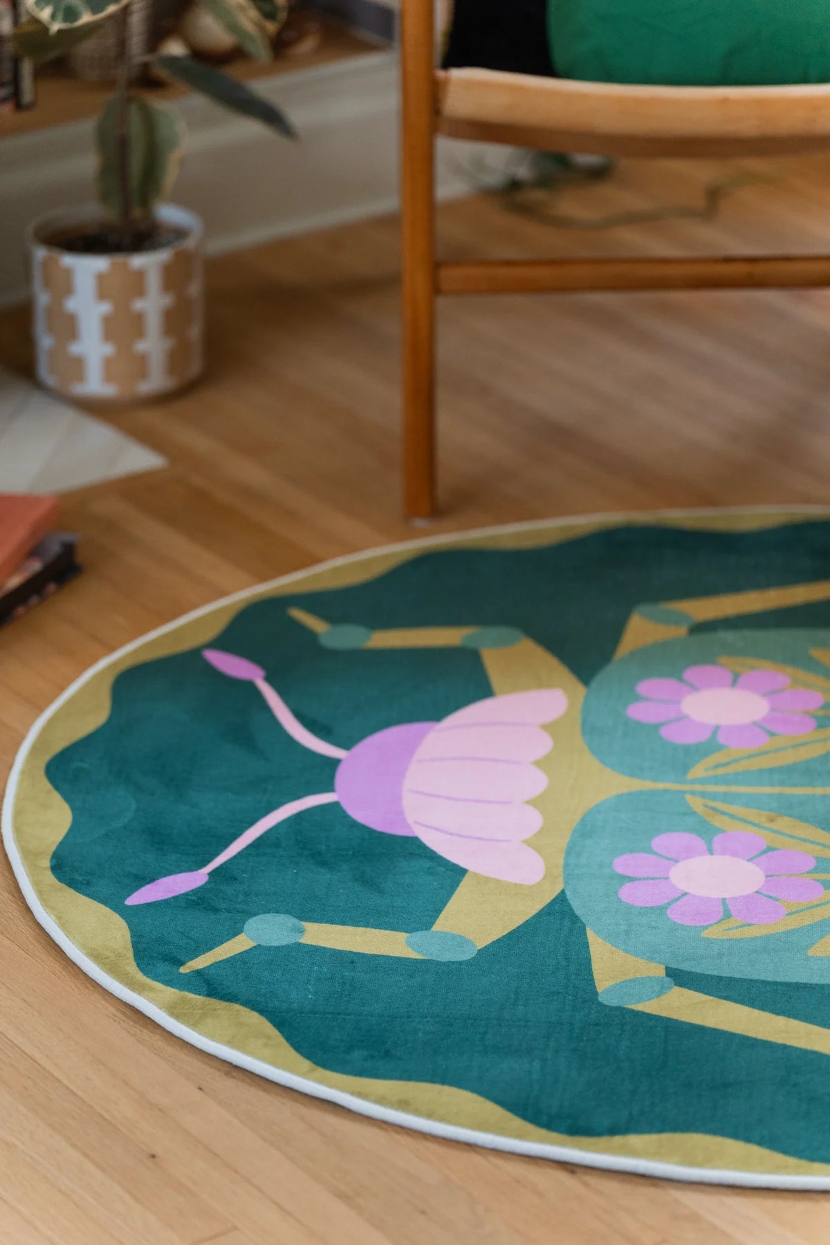 Partial view of the round floral rug under a chair leg, with a pink flower cluster and curving stem detail