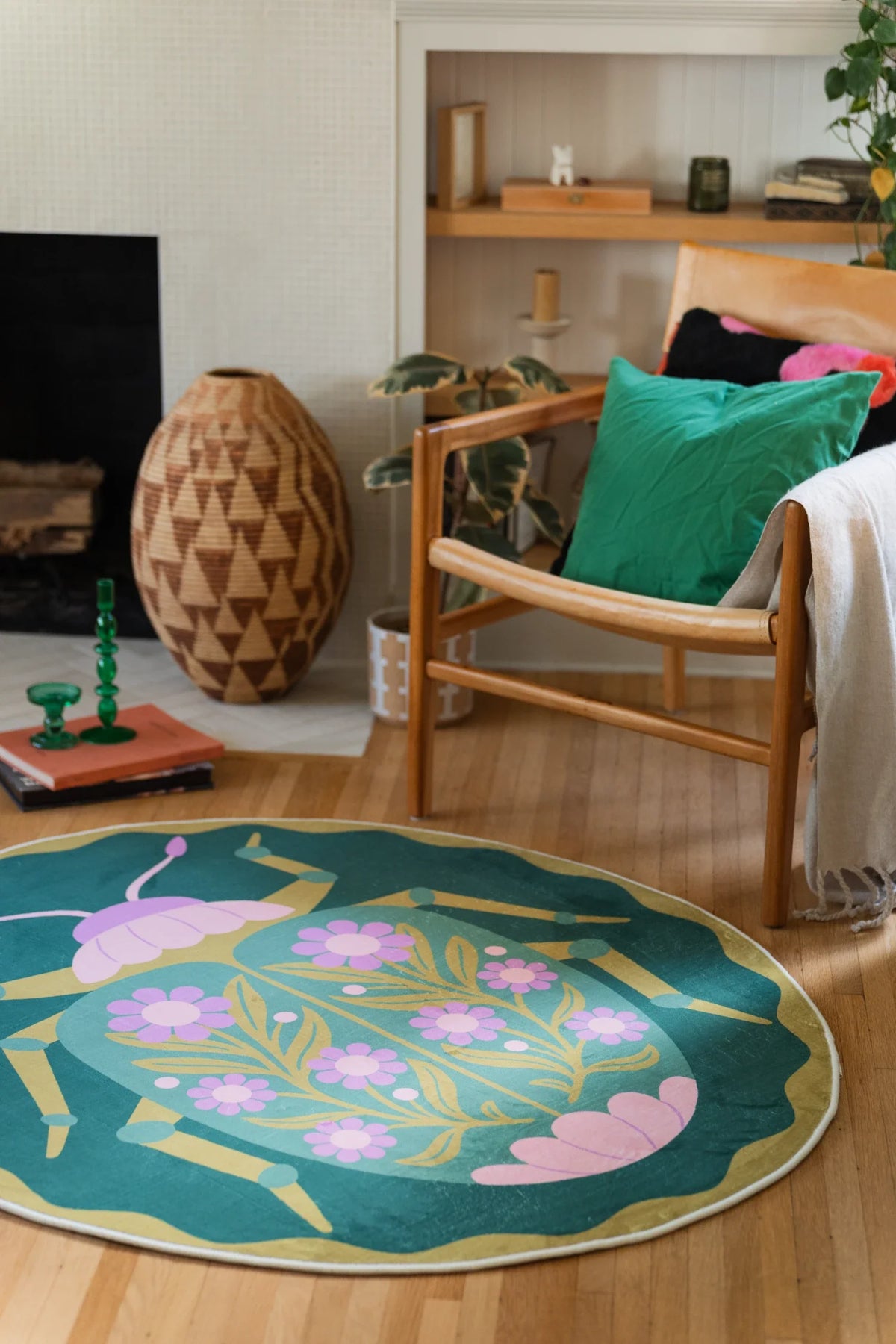 Green round area rug beside a wood chair with a bright green cushion, featuring pink blossoms and mirrored floral shapes