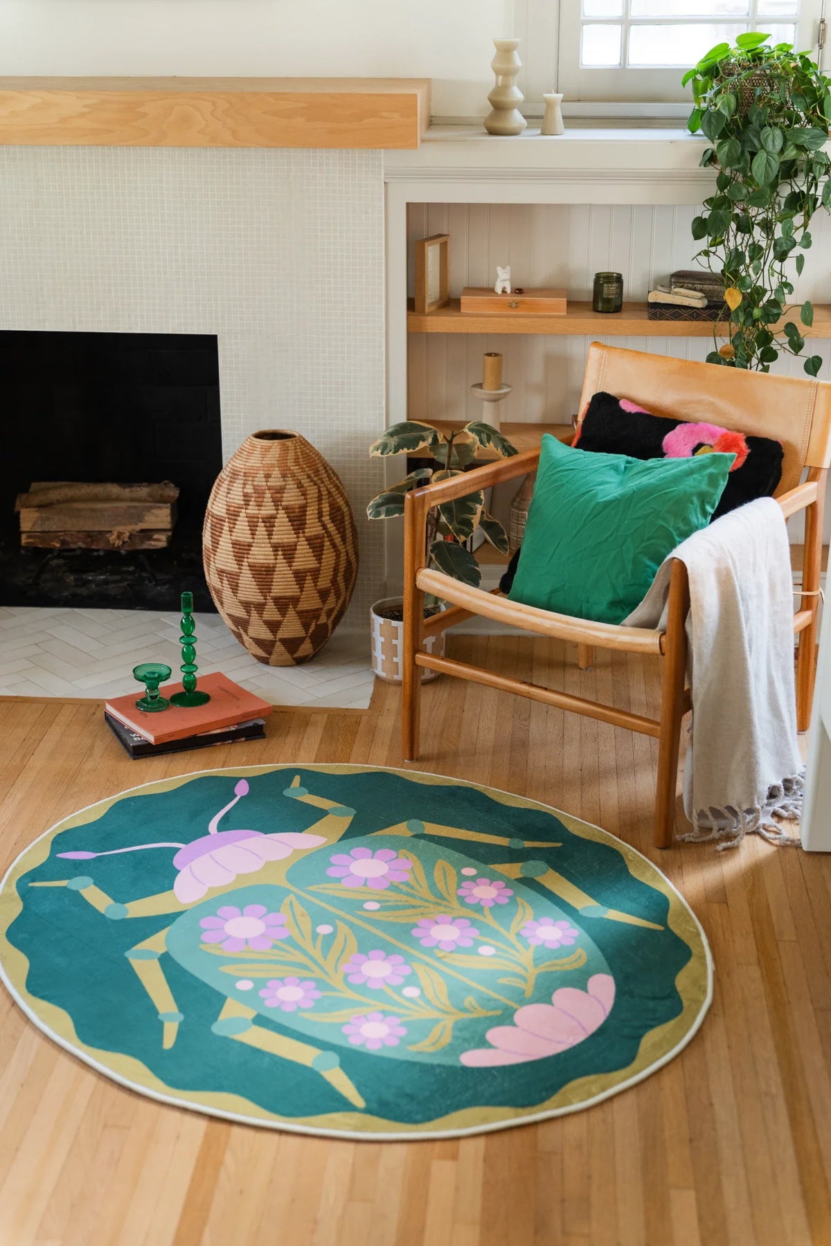 Graphic floral round rug near the fireplace and woven vase, with a scalloped green border and layered pink blooms