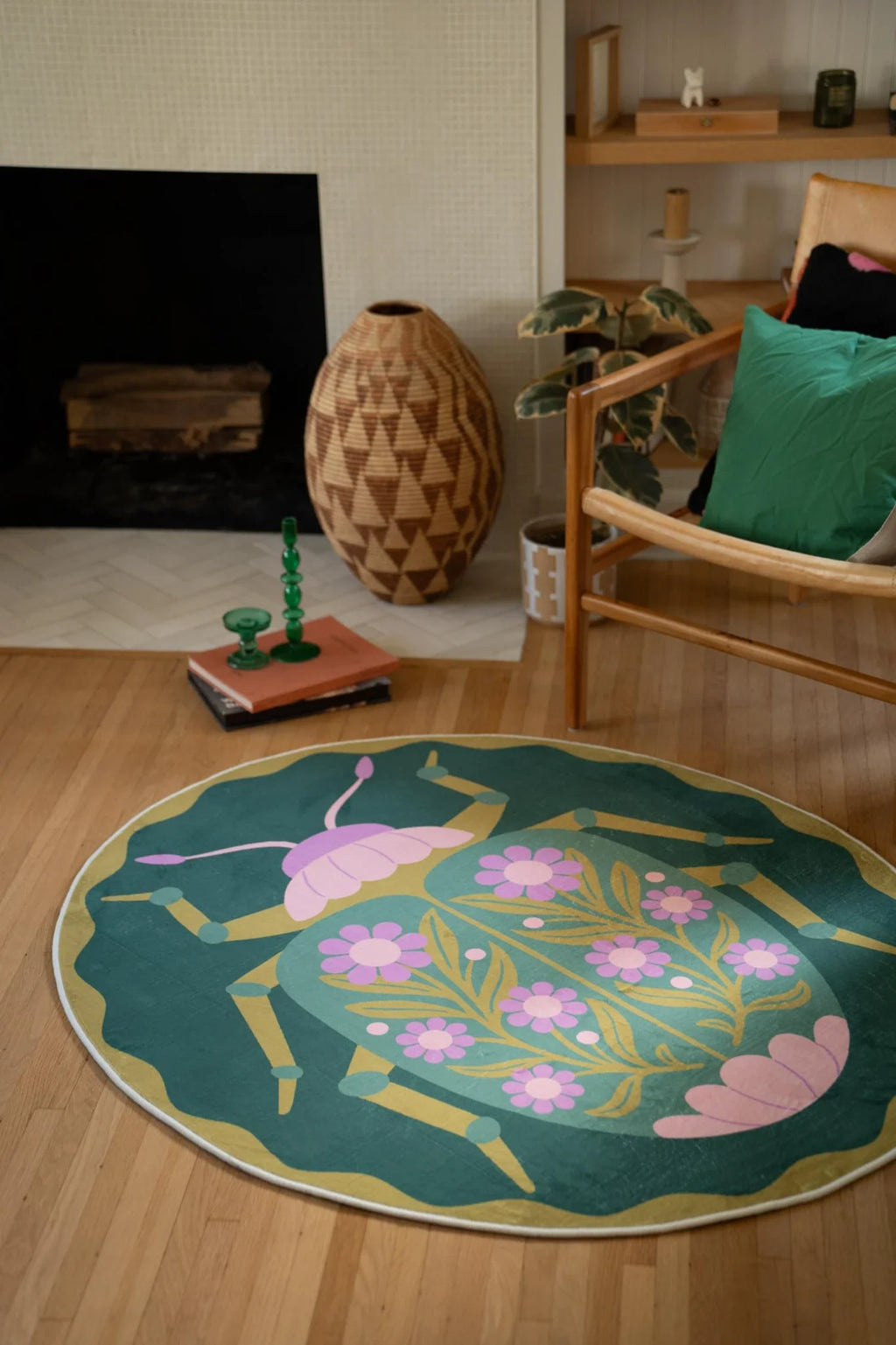 Beetle inspired floral round rug placed between the fireplace and chair, with a scalloped edge on a light wood floor