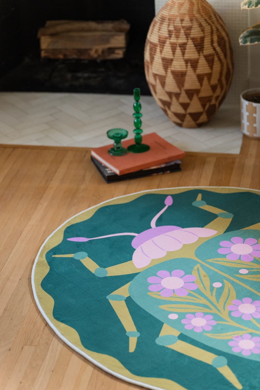 Corner crop near the hearth, highlighting the rug's deep green field, pale stems, and scalloped outer edge