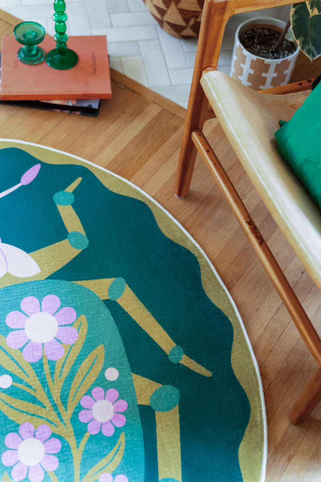 Close detail beside the chair, with pink flower shapes and pale green linework crossing the green round rug