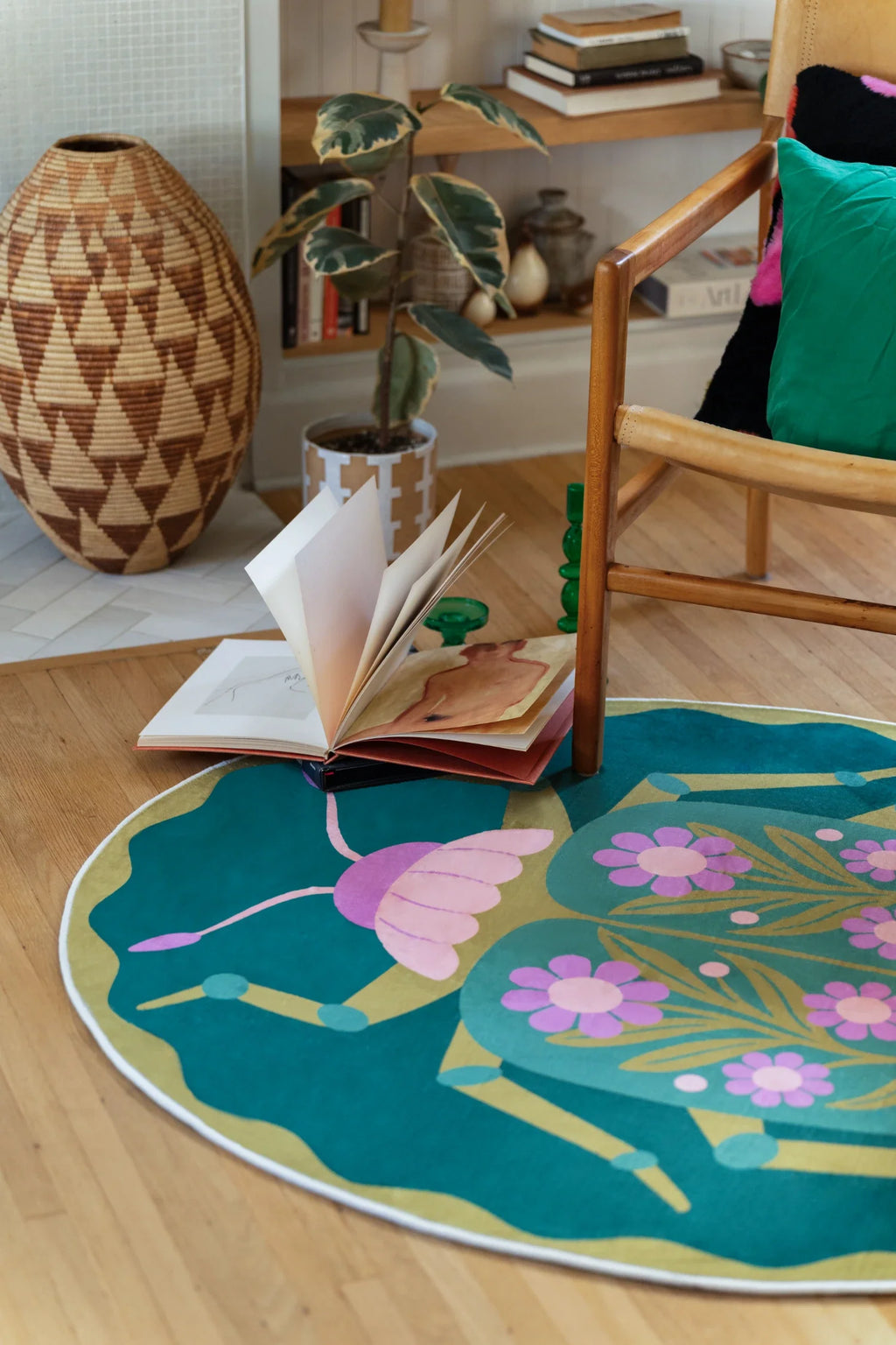 Open book next to the floral round rug, showing the scalloped edge and beetle inspired symmetry on the floor