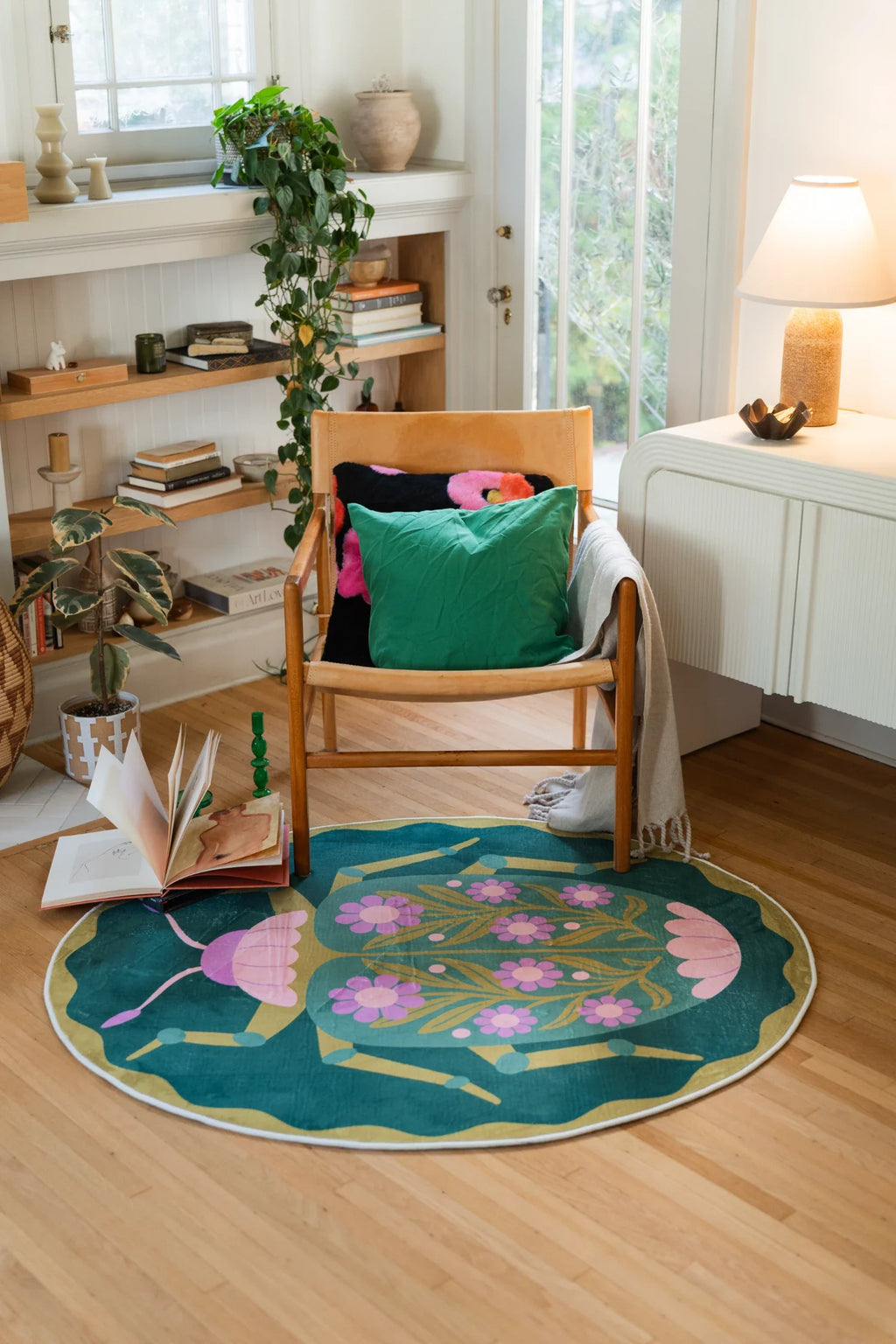 Round beetle rug in a modern reading corner beside a floor lamp and open shelving, adding a playful focal point