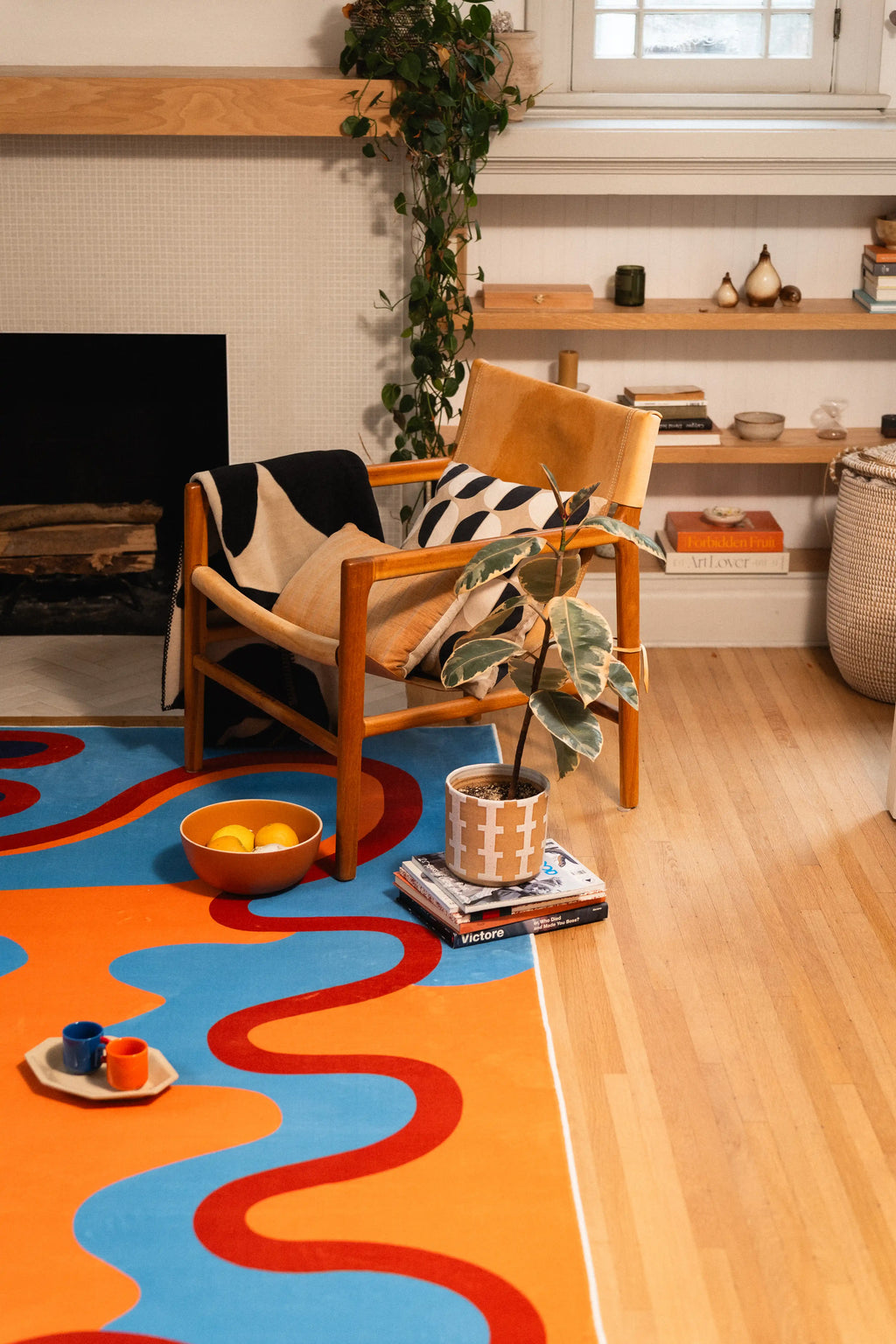 From the side of the room, the rug runs past a wooden chair toward the fireplace with a tea set near its edge.