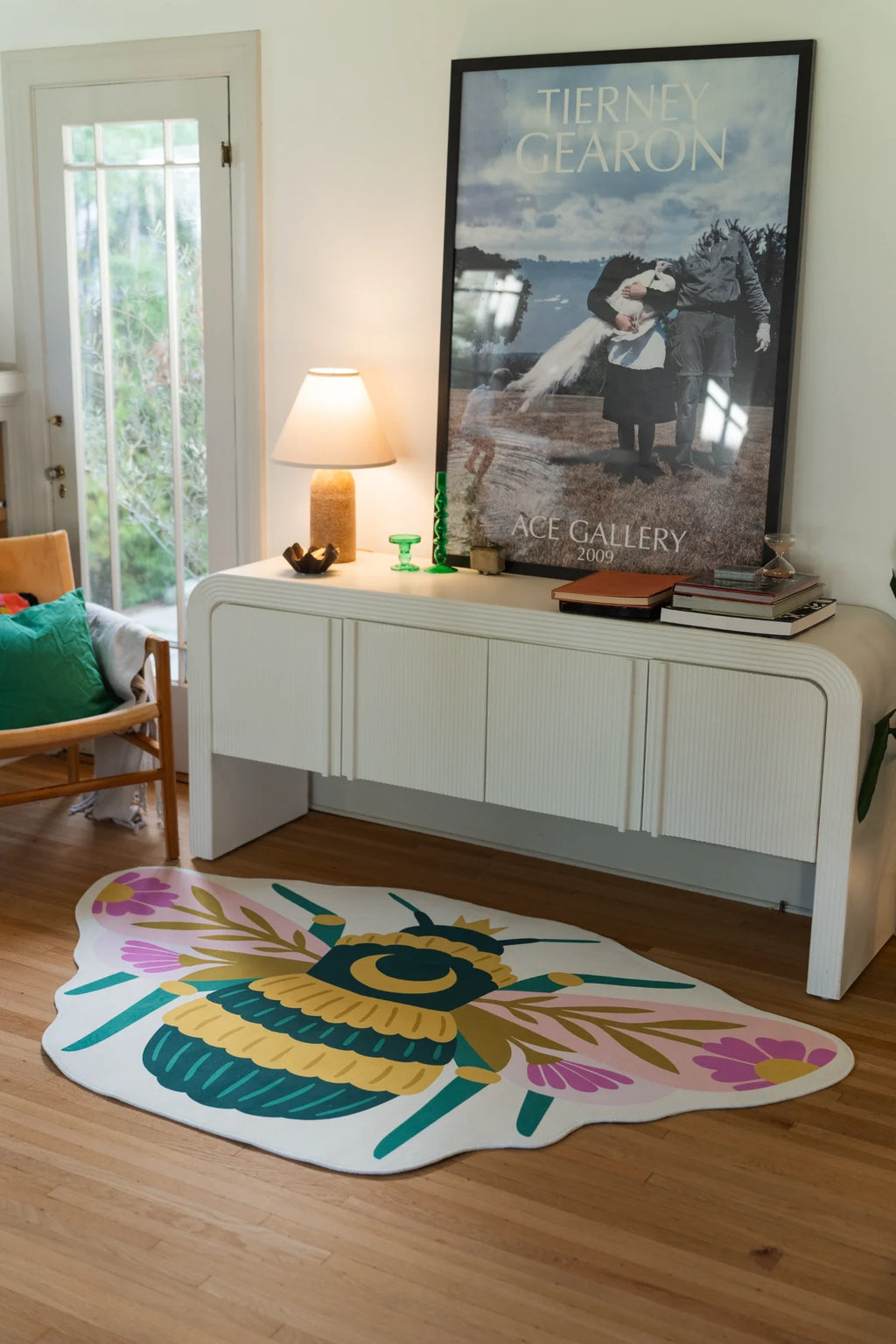 Graphic queen bee rug beside a white media console in a bright room, with layered wings and floral wing accents