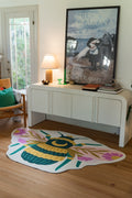 Graphic queen bee rug beside a white media console in a bright room, with layered wings and floral wing accents