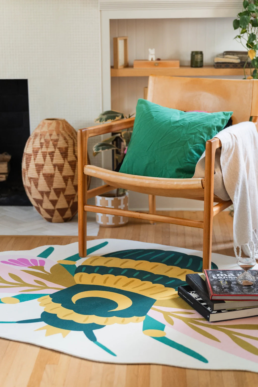 Partial view of the bee shaped rug under a wood chair, showing teal stripes, pale wings, and pink flower motifs