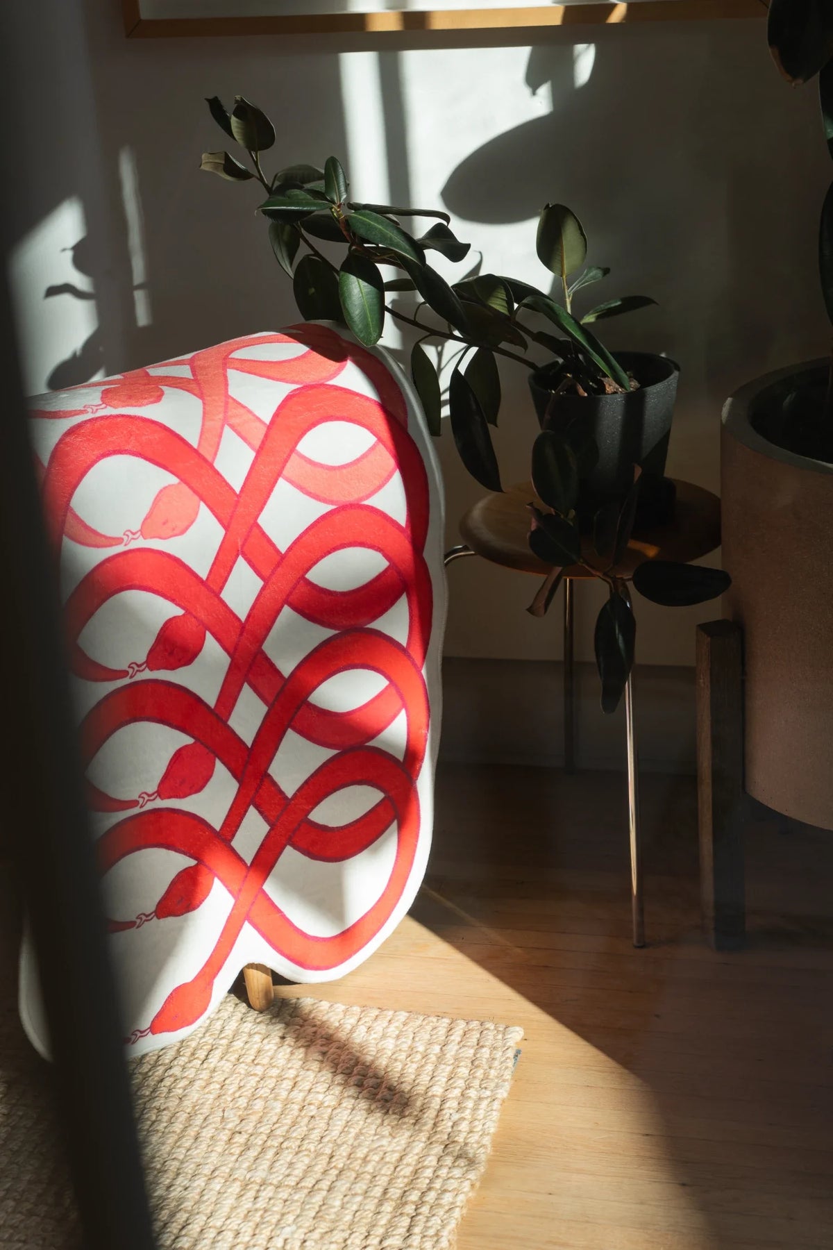 Vertical view of the abstract runner in sunlight, with interwoven red loops against a soft blush background
