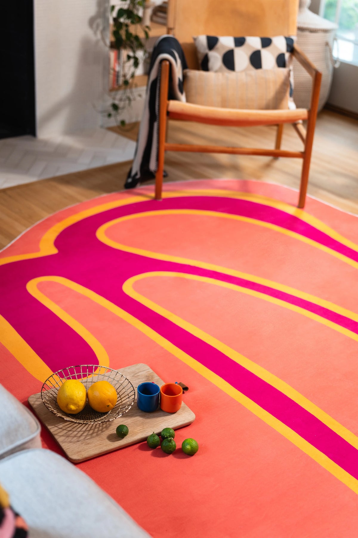 Orange abstract rug beneath a wooden chair with lemons and colorful toys arranged on a wooden board.