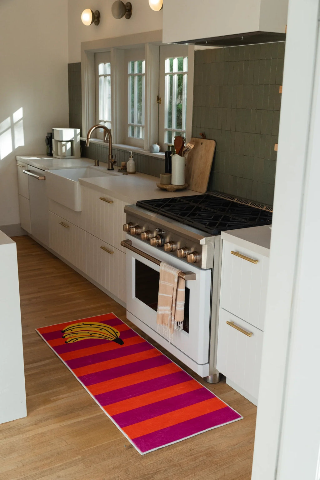 Banana runner rug in a bright kitchen with white cabinets, a stainless oven, and bold pink and orange stripes