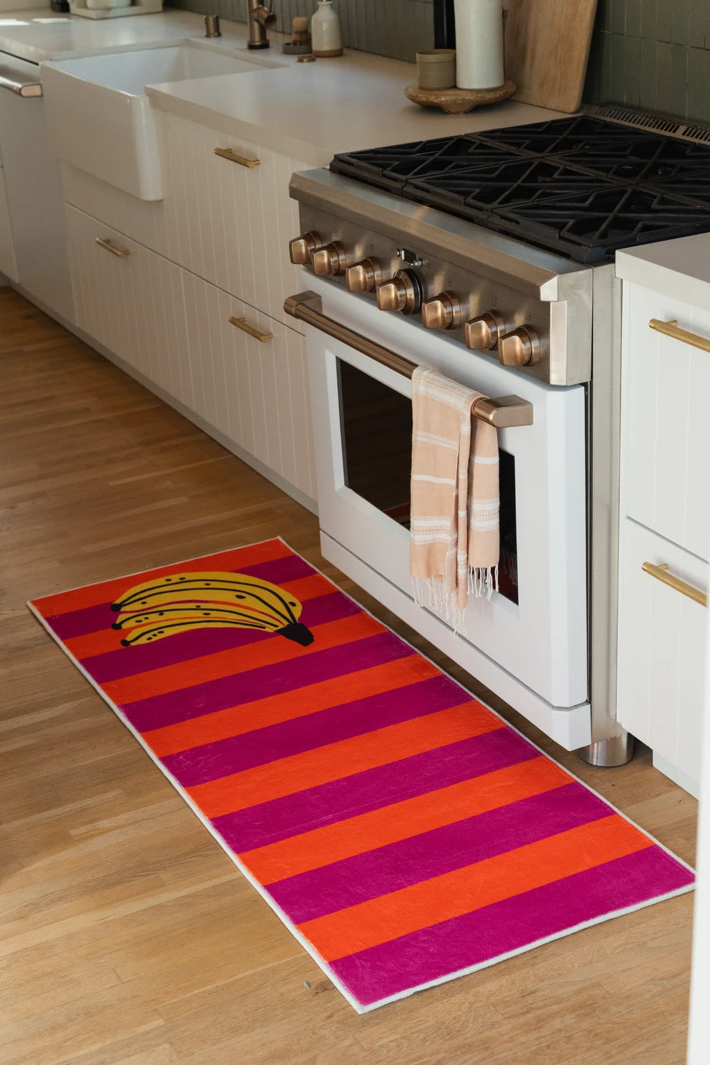 Banana runner rug beside a white oven, showing bold horizontal stripes and a playful fruit graphic