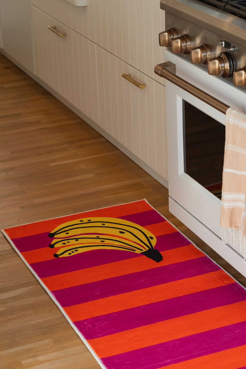 Close up of the runner rug with pink and orange stripes and a yellow banana motif near the corner