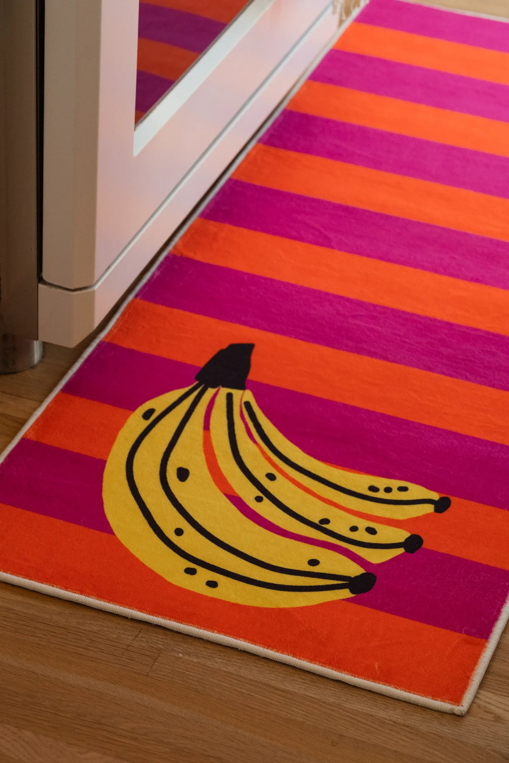 Close up of the Colorful Striped Banana Fruit Runner Rug with yellow bananas on vivid pink and orange stripes