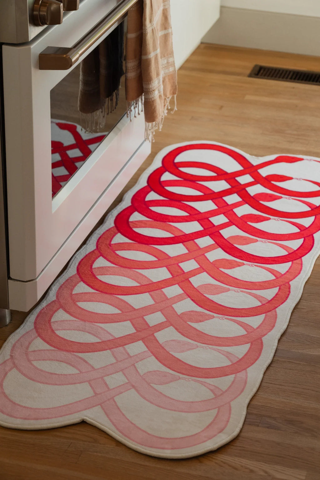 Close view of the runner beside the oven door, showing layered red curves and rounded loop shapes