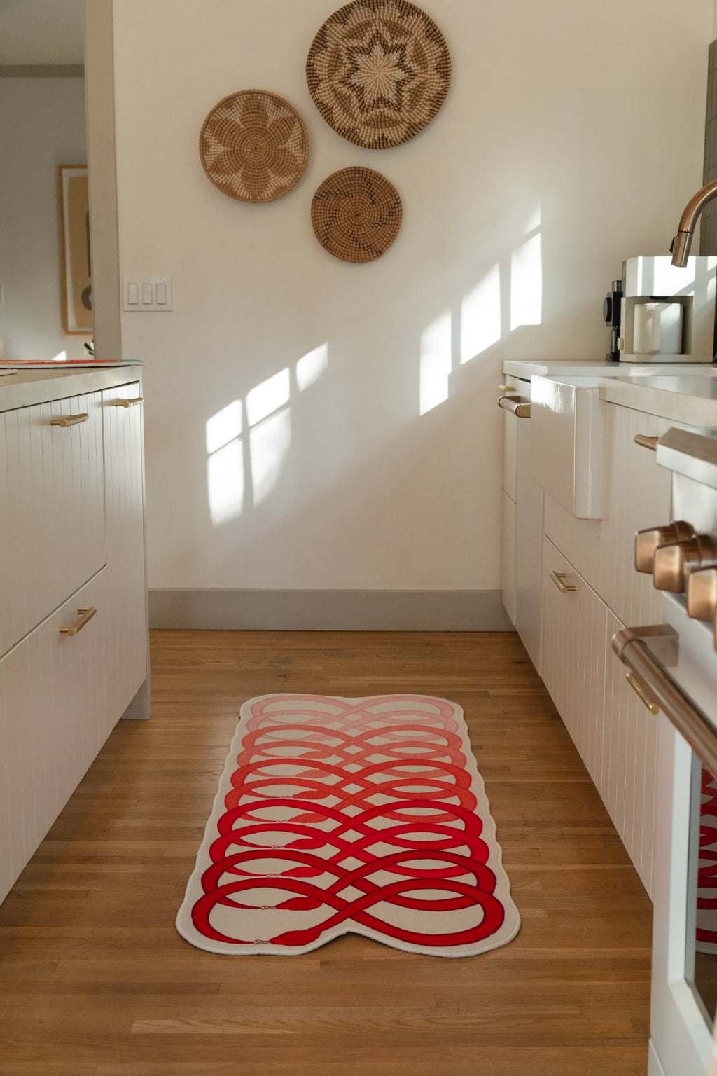 Graphic snake runner rug stretched through a bright kitchen walkway, with red loops repeated across a pale pink ground