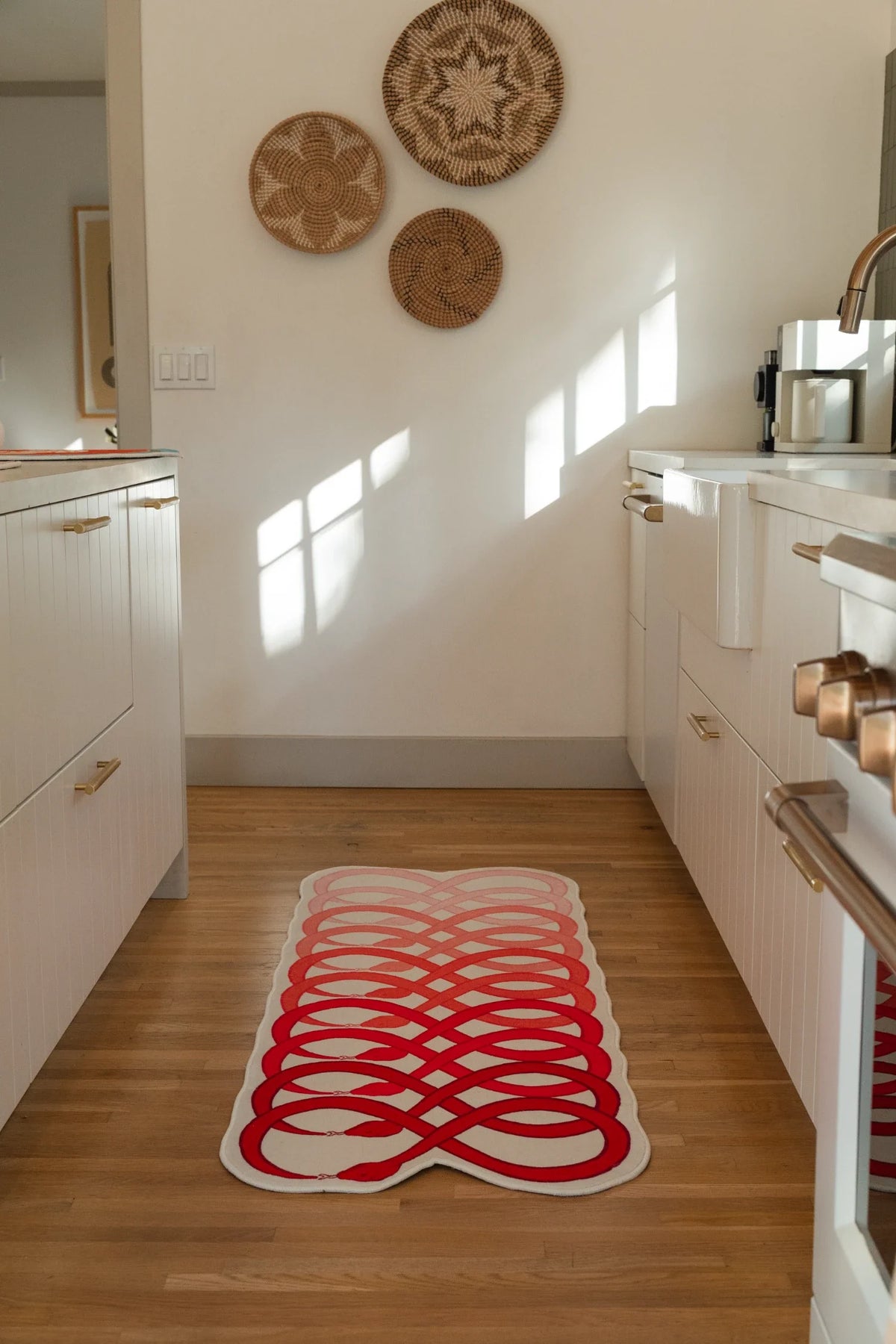 Graphic snake runner rug stretched through a bright kitchen walkway, with red loops repeated across a pale pink ground