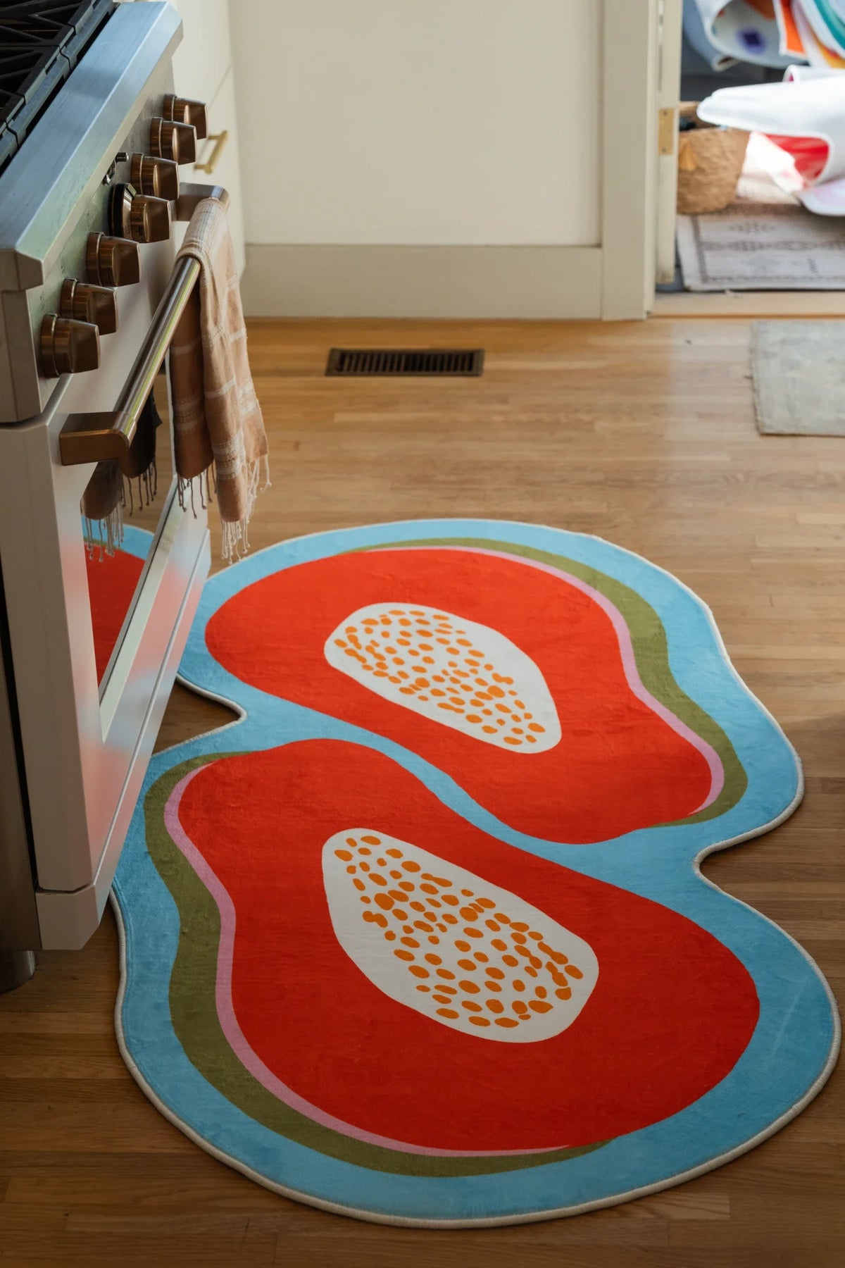 Papaya Orange Irregular Fruit Rug in a kitchen walkway beside a white oven on a light wood floor