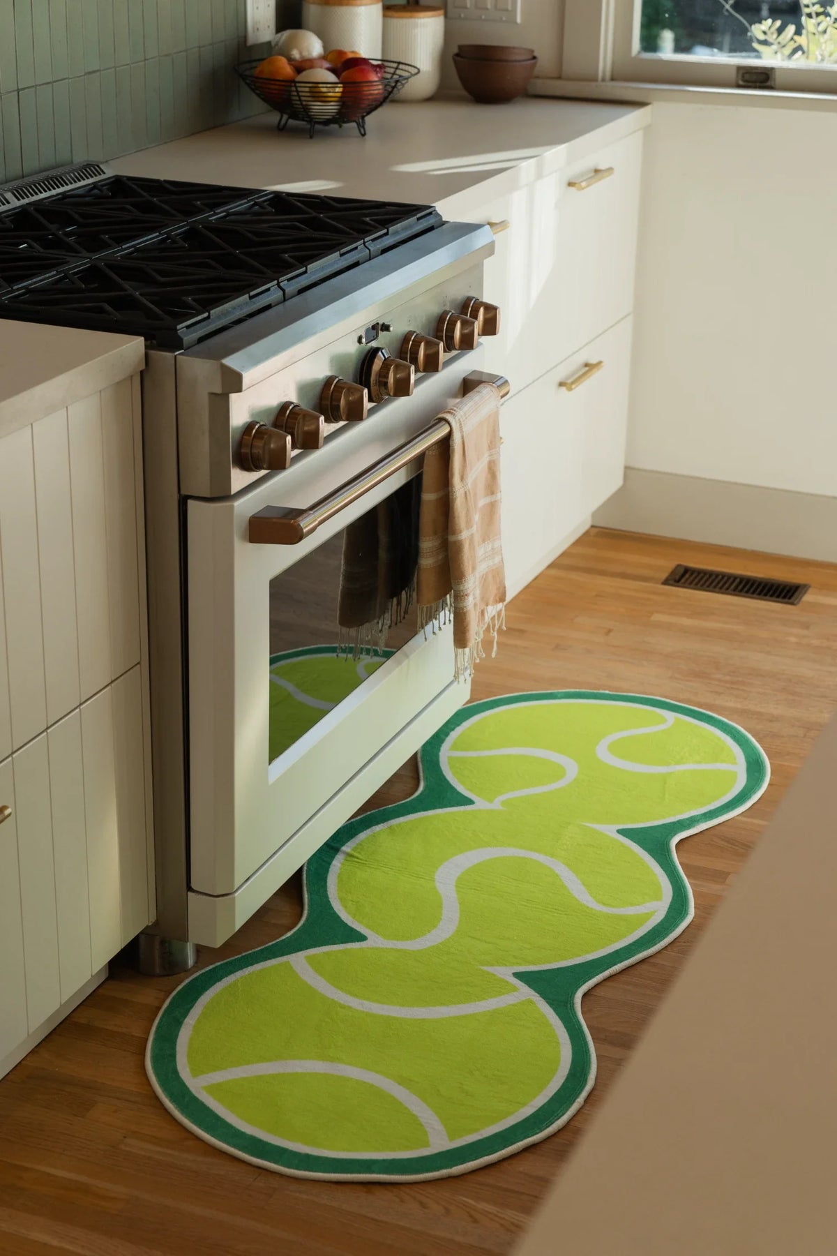 Green Irregular Tennis Runner Rug by Zoe Wodarz beside a white kitchen oven on a light wood floor