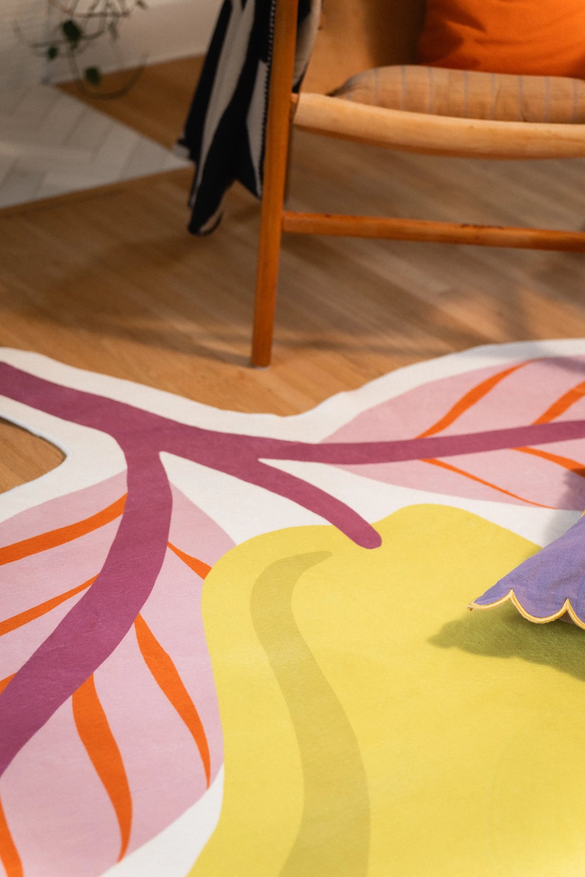 Pink pear leaves with orange veins and a mauve stem beside a wooden chair, with part of the yellow fruit visible.